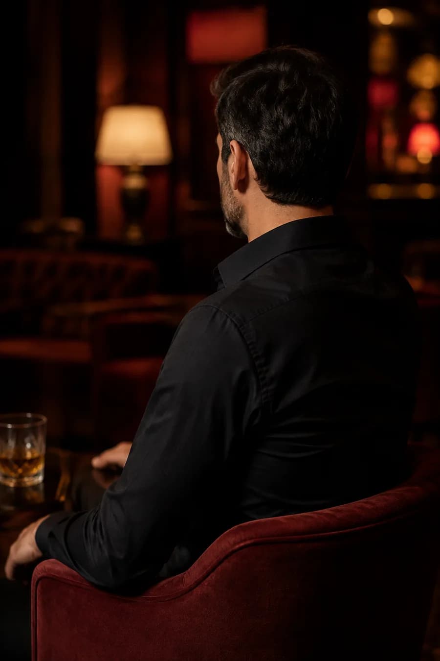 Homem adulto de camisa preta visto de costas em um lounge